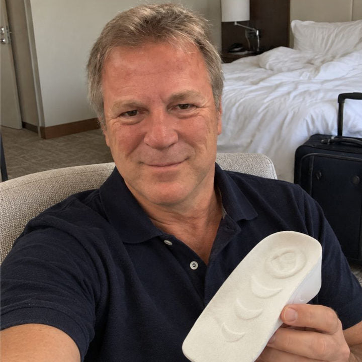Man in a navy polo holding a white HighPads insert while traveling
