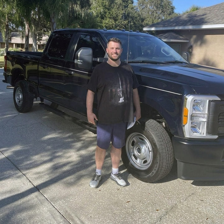 Man standing beside his work truck in everyday sneakers